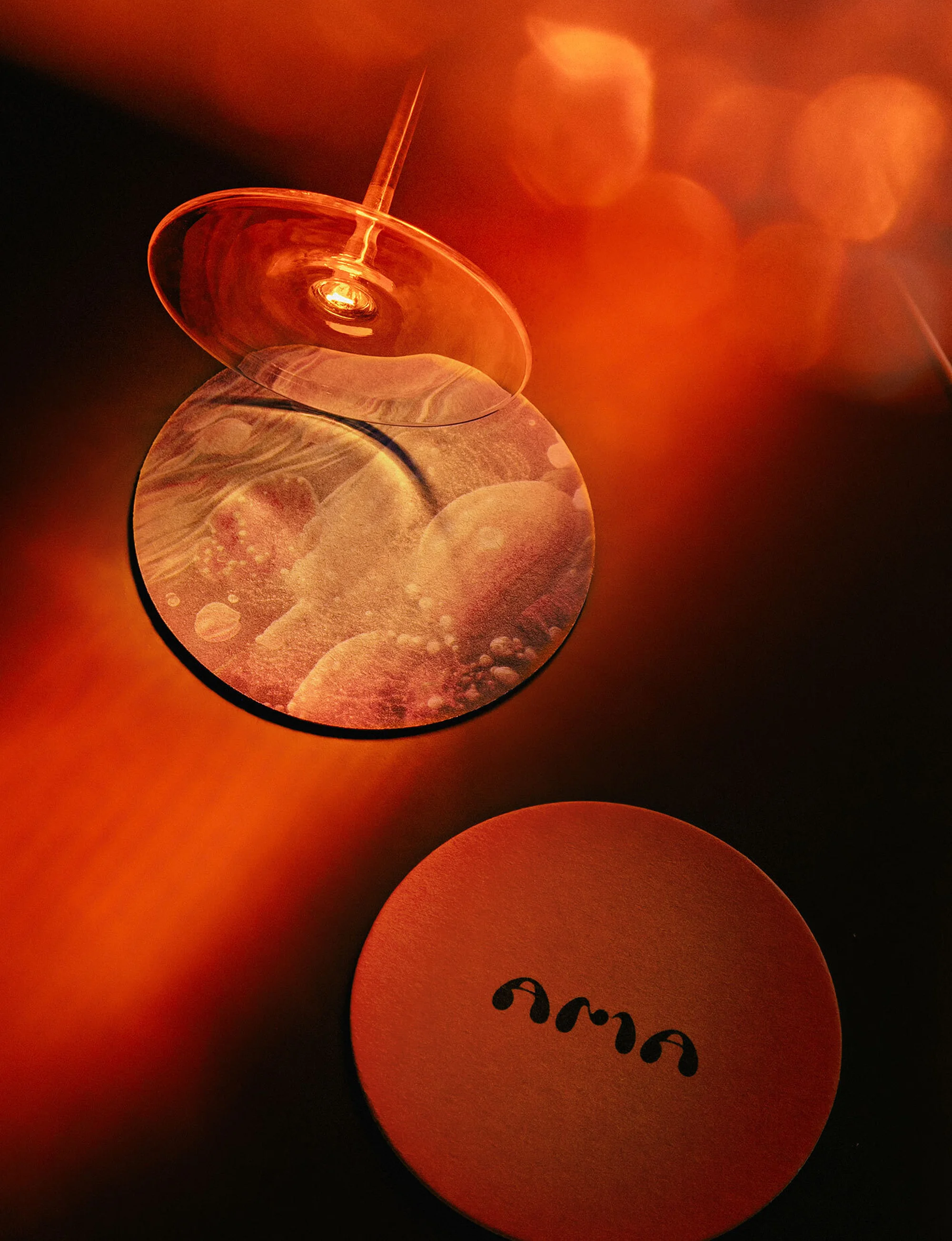 Abstract close-up shot of drink glasses with creative lighting and composition, featuring circular patterns and the text 'ama'.