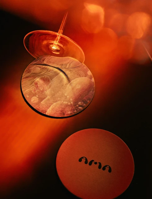 Abstract close-up shot of drink glasses with creative lighting and composition, featuring circular patterns and the text 'ama'.
