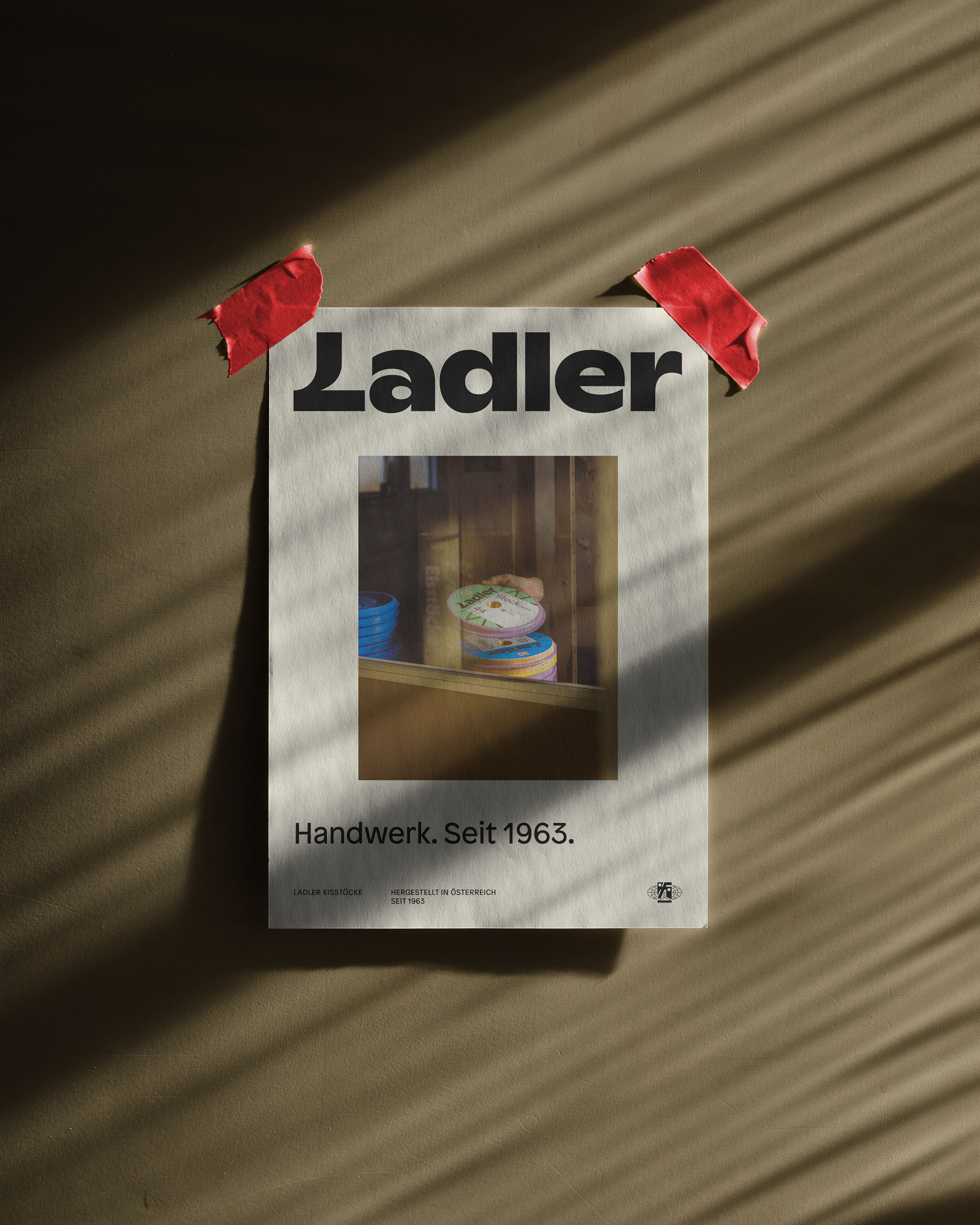 Poster for Ladler is taped to a wall, featuring an image of shelves and text. Soft lighting casts shadows from a window blind.
