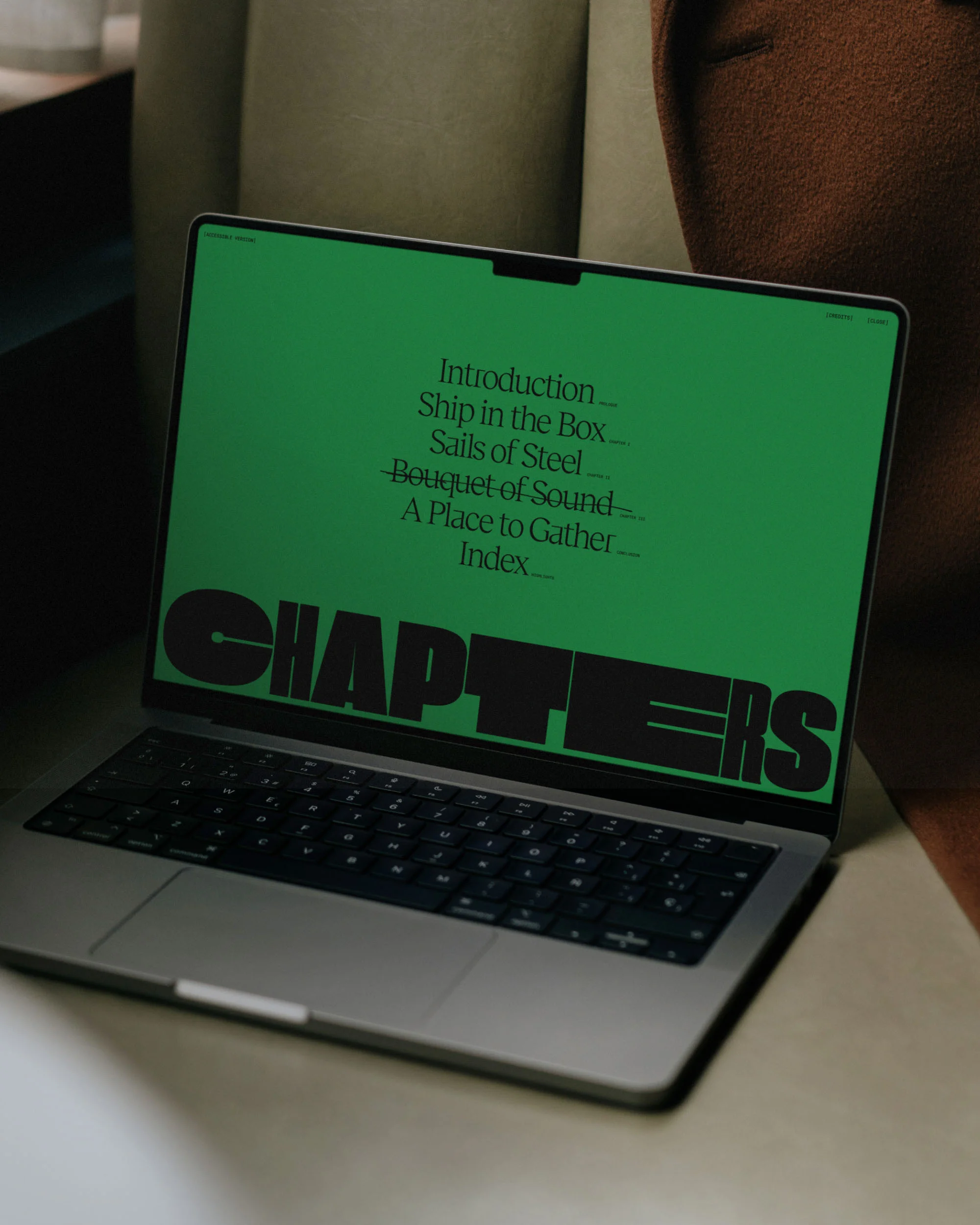 Silver laptop screen displays a green background with the word "CHAPTERS" and a table of contents listed on the screen.