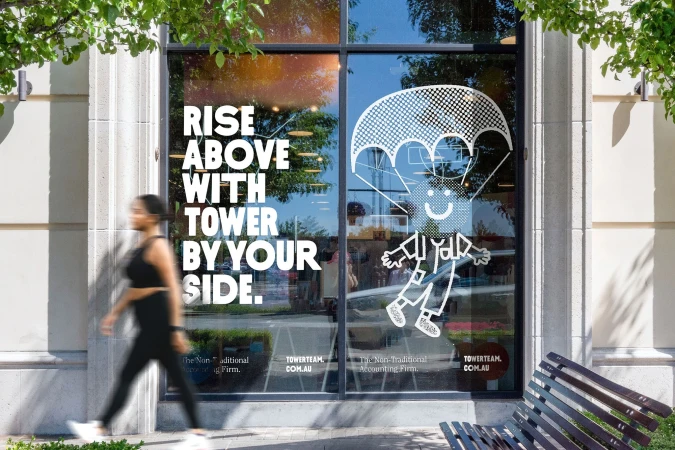 Woman walking past a window with a graphic illustration of a person with a parachute, and marketing text for accounting firm.