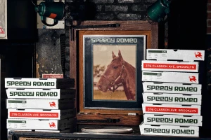 Stacks of branded pizza boxes flank a framed horse photograph against a dark brick restaurant wall