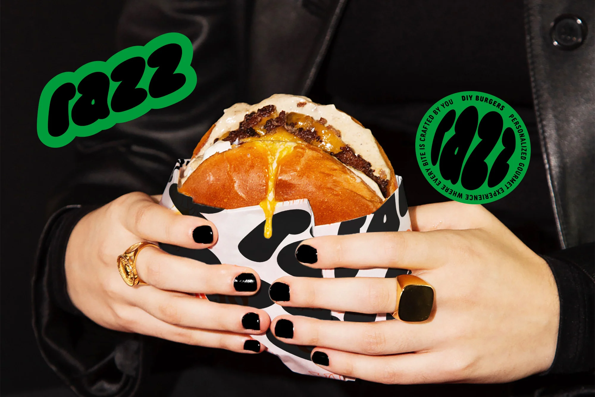 Close-up of a burger held by woman with black nail polish and rings, with green and black logo graphics on a dark background.