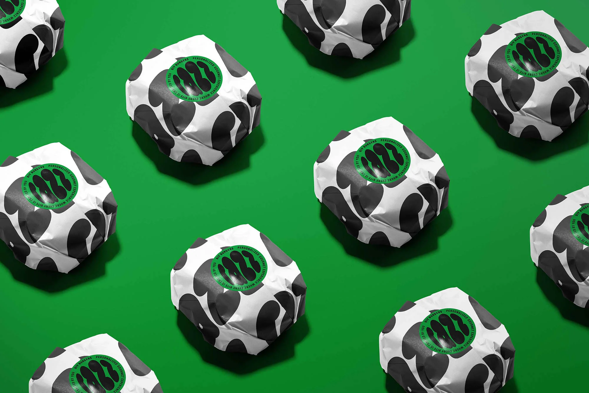 Overhead shot of multiple wrapped food items with a cow pattern on a vibrant green background, showcasing a modern and playful food presentation.