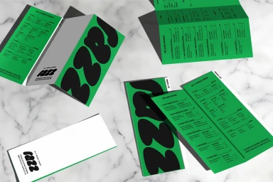 Green and white branded restaurant menus for Razz Burger laid out flat and folded on a grey marble surface