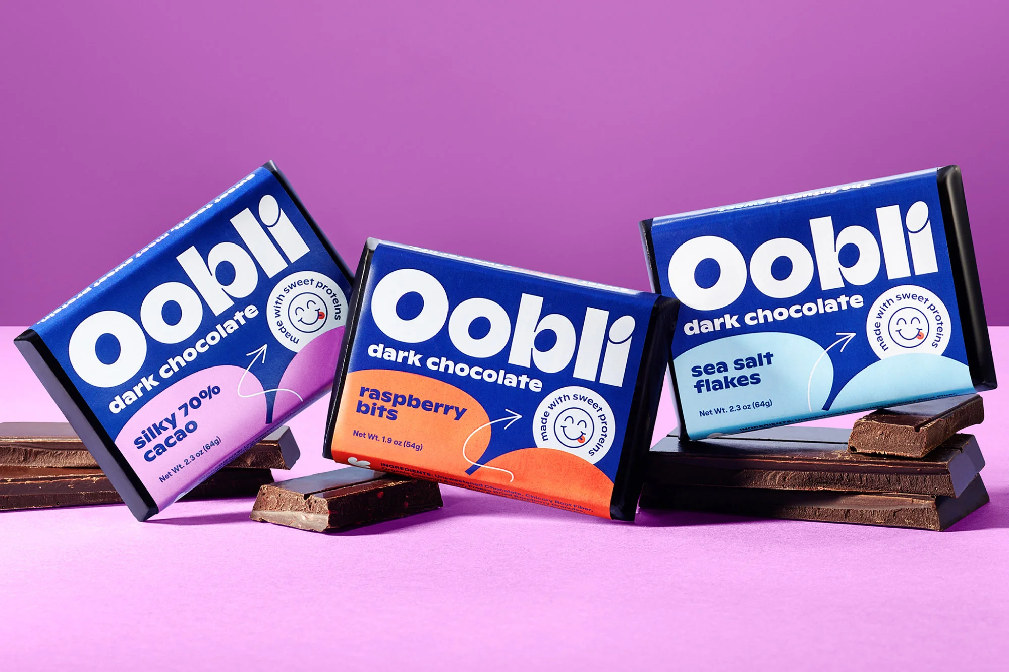 Three Oobli dark chocolate bars with different flavors (silky 70% cacao, raspberry bits, and sea salt flakes) against purple background.