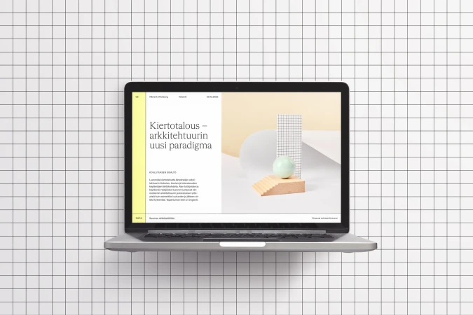 Laptop displaying a sleek website design featuring modern typography and geometric shapes, set against a clean, minimalist background.