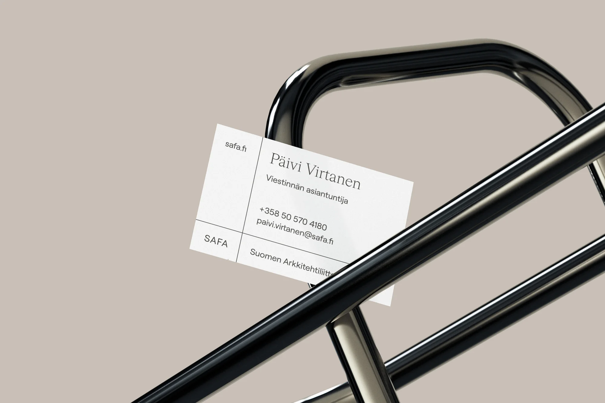 Business card on a polished metal rack, featuring the name Päivi Virtanen and contact information against a soft beige backdrop.