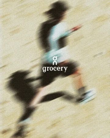 Blurred motion shot of an adult running on a tan surface, wearing athletic shoes and a white top, under the brand name 'grocery'.