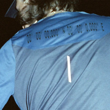 Close-up of a person wearing a blue athletic shirt featuring coordinates, showcasing sportswear and technical apparel details.