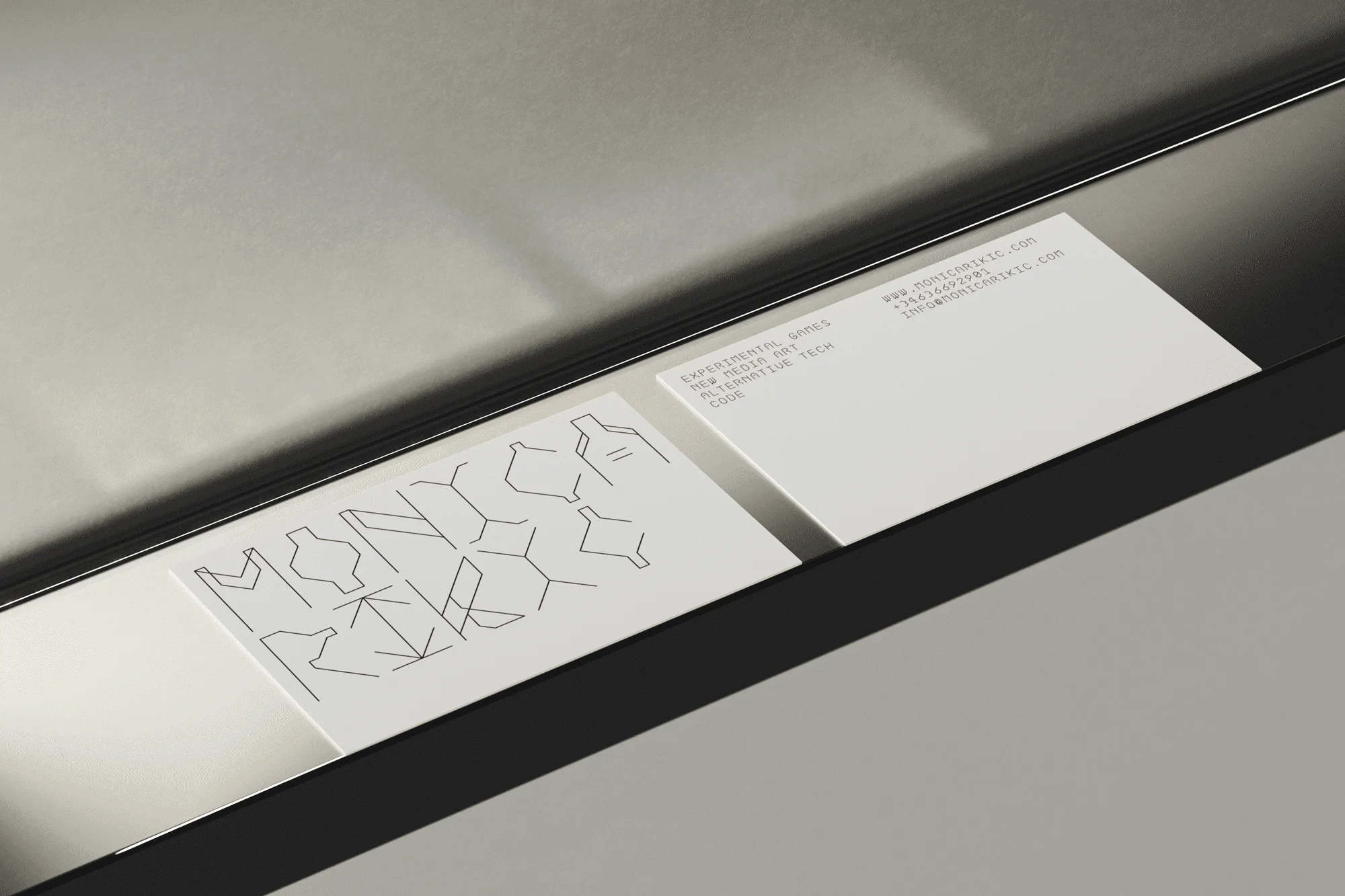 Two business cards, one with a geometric linear design, the other with contact info, displayed in a sleek, minimalist setting.