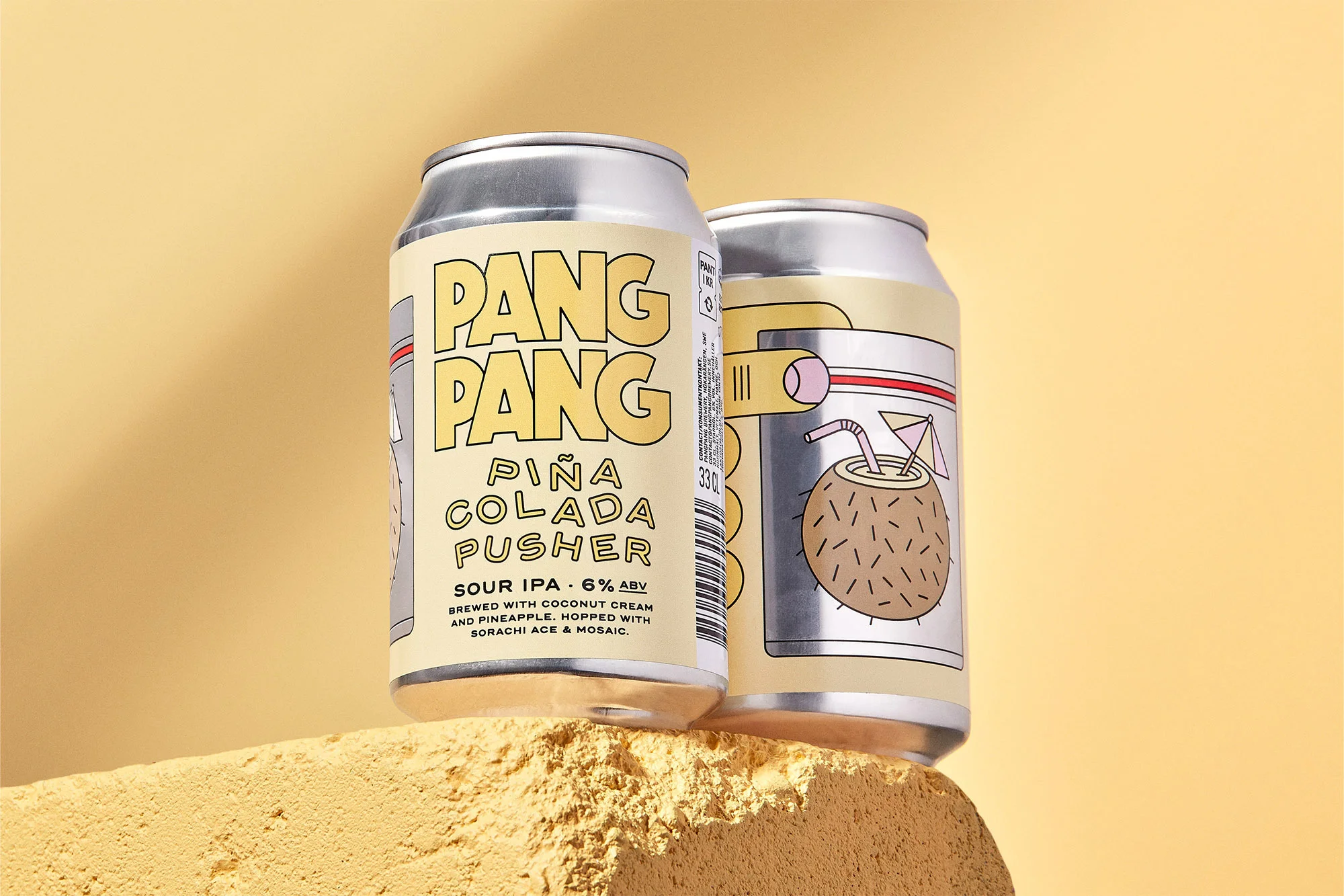 Two Pang Pang Piña Colada Pusher Sour IPA beer cans on a yellow podium against a pale yellow background in a studio product shot.