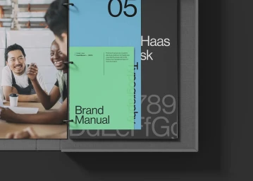 Close-up of an open ring binder displaying a FasterLines brand manual with colorful typographic layouts and pages.