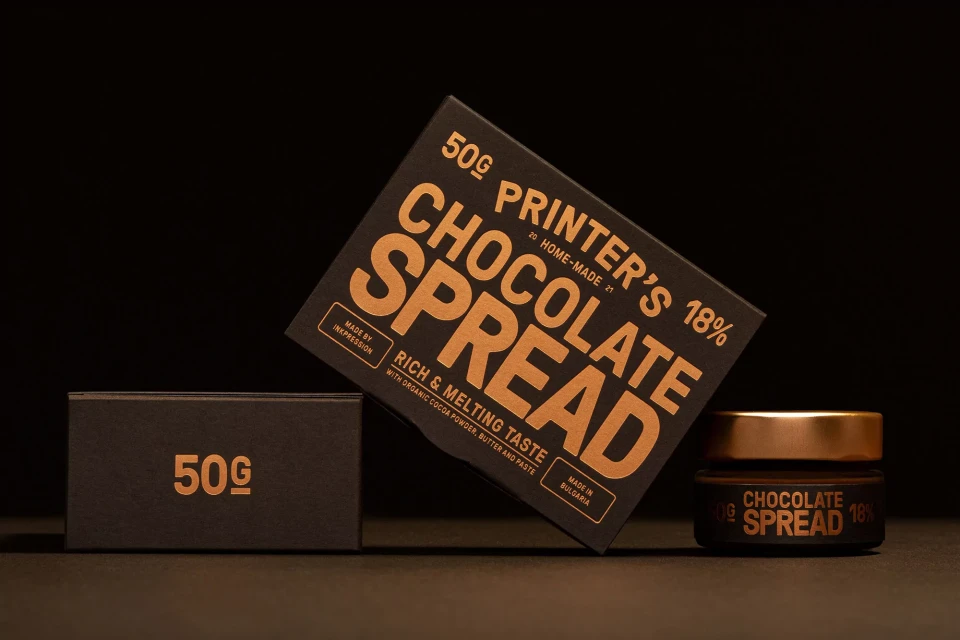 Chocolate spread product photography featuring a black box, jar, and smaller box with gold text on a black background.