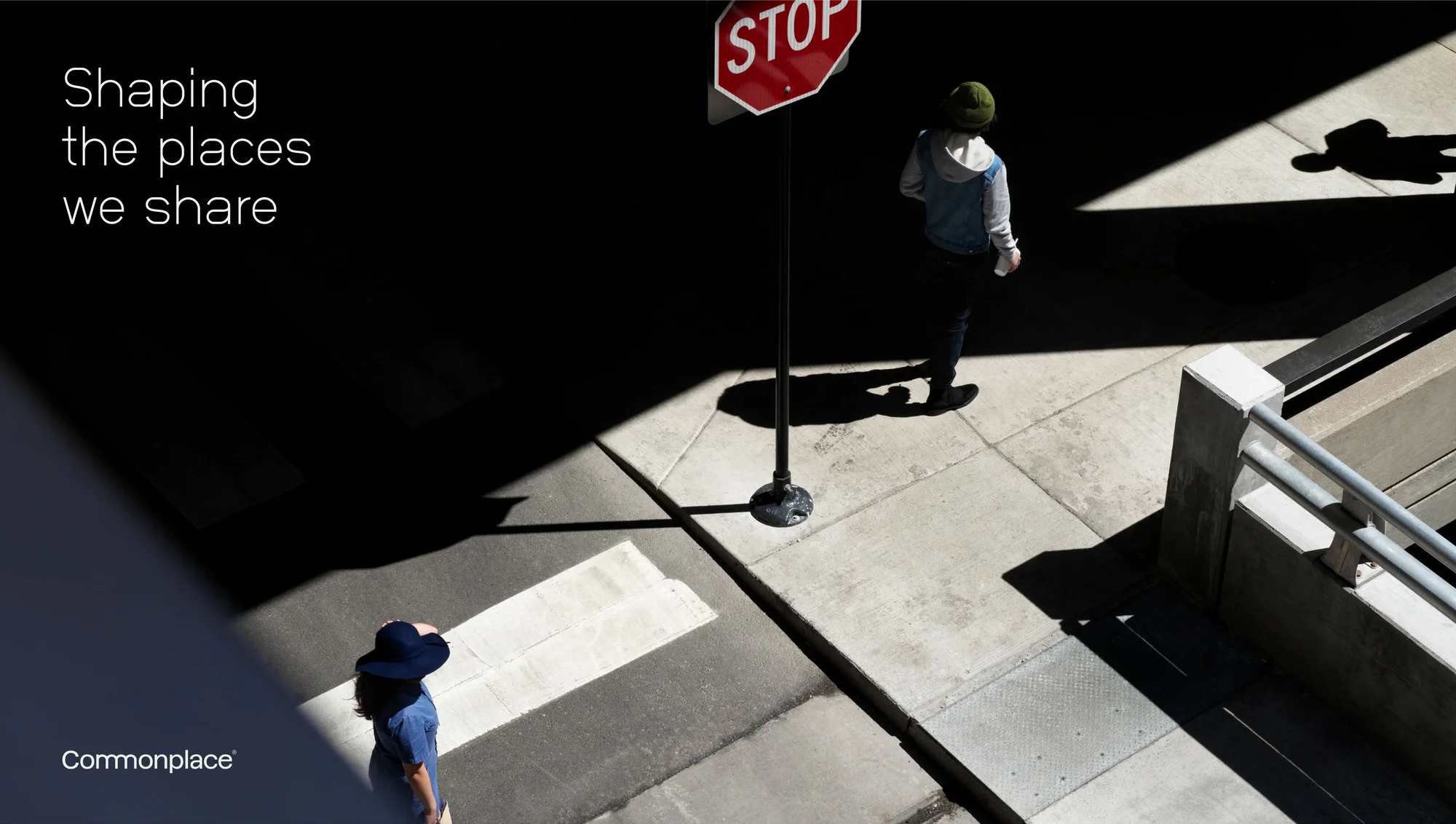 High-angle view of two people in an urban setting with shadows, one near a stop sign, emphasizing shapes, lines, and urban design.