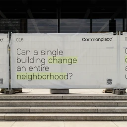 Large white printed construction barrier banner with typography reading Can a single building change an entire neighborhood