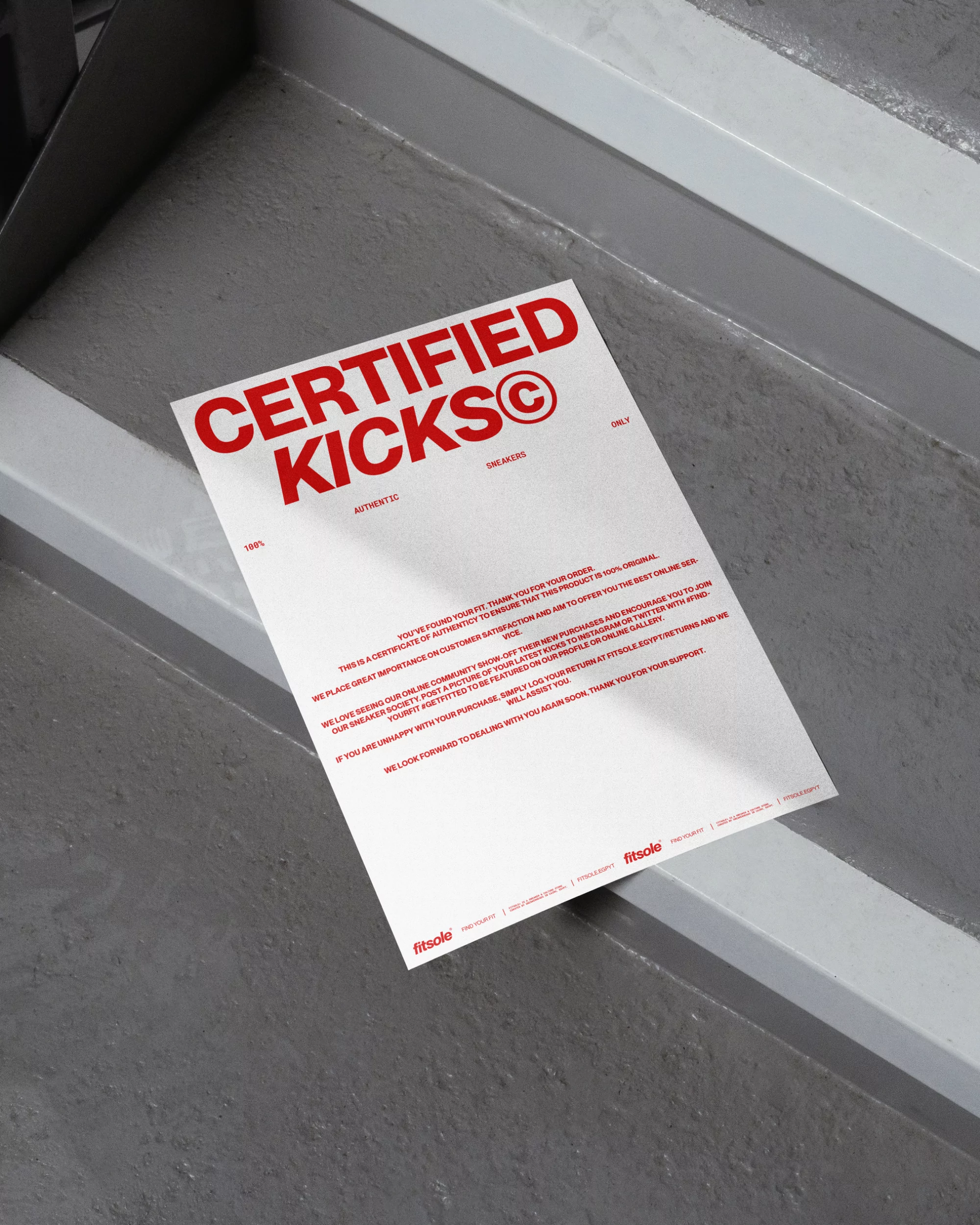 White paper with red text that reads Certified Kicks laying on grey stairs, with shadows. The paper appears to be a certificate.