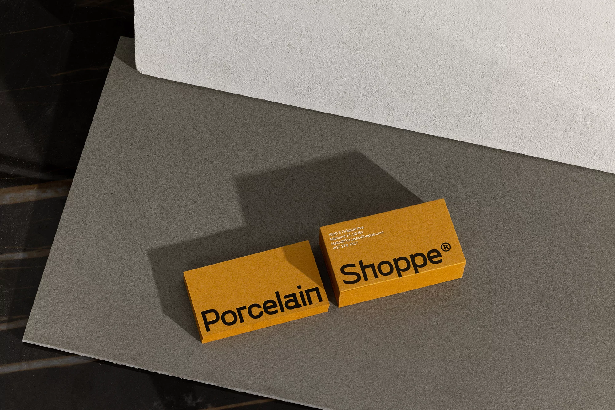 Two yellow cards with 'Porcelain' and 'Shoppe' text on a grey and black surface, clean and modern design, product advertisement.
