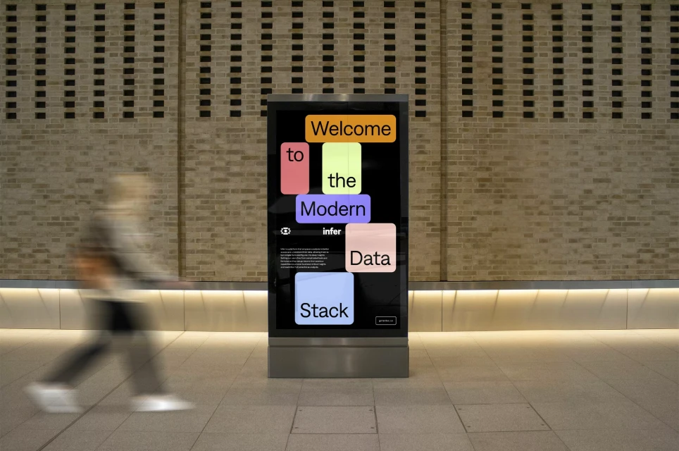 Illuminated advertising kiosk with colorful text 'Welcome to the Modern Data Stack' stands on a tiled floor with a blurred person passing by.