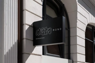 Black rectangular storefront sign mounted on a white neoclassical building exterior displaying DistroMono branding.