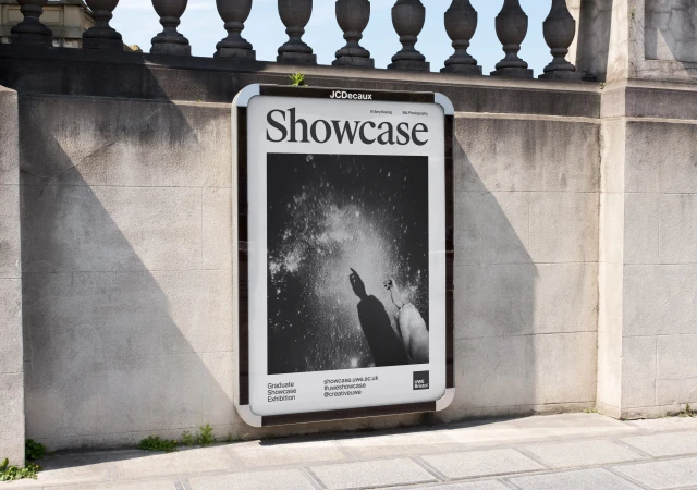 Outdoor advertising billboard showcasing monochrome photography on a stone wall with classic balustrade under bright natural light.