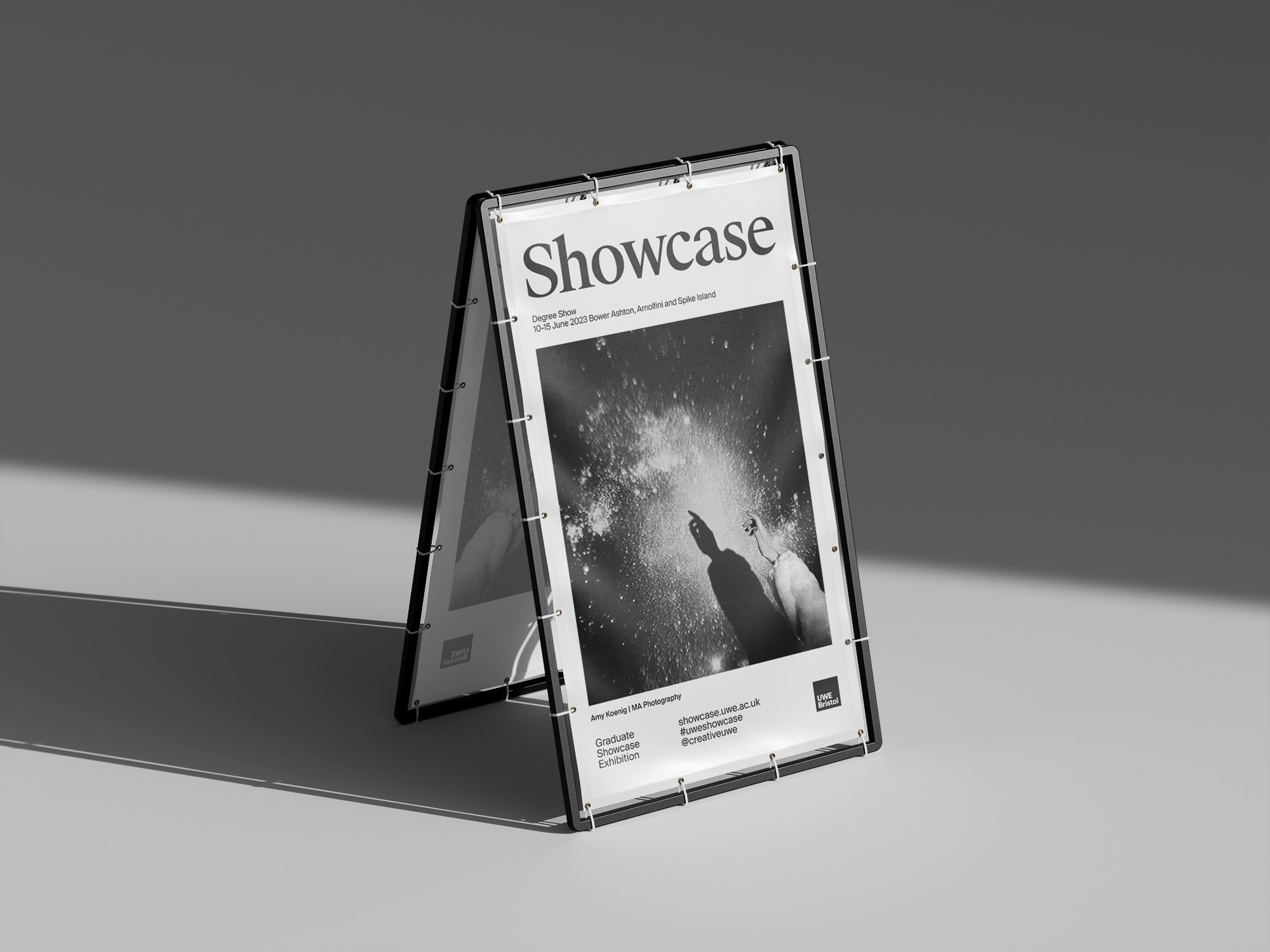 A-frame sign displaying a black and white photograph. The sign is angled with a gray background, and text is visible on the poster.