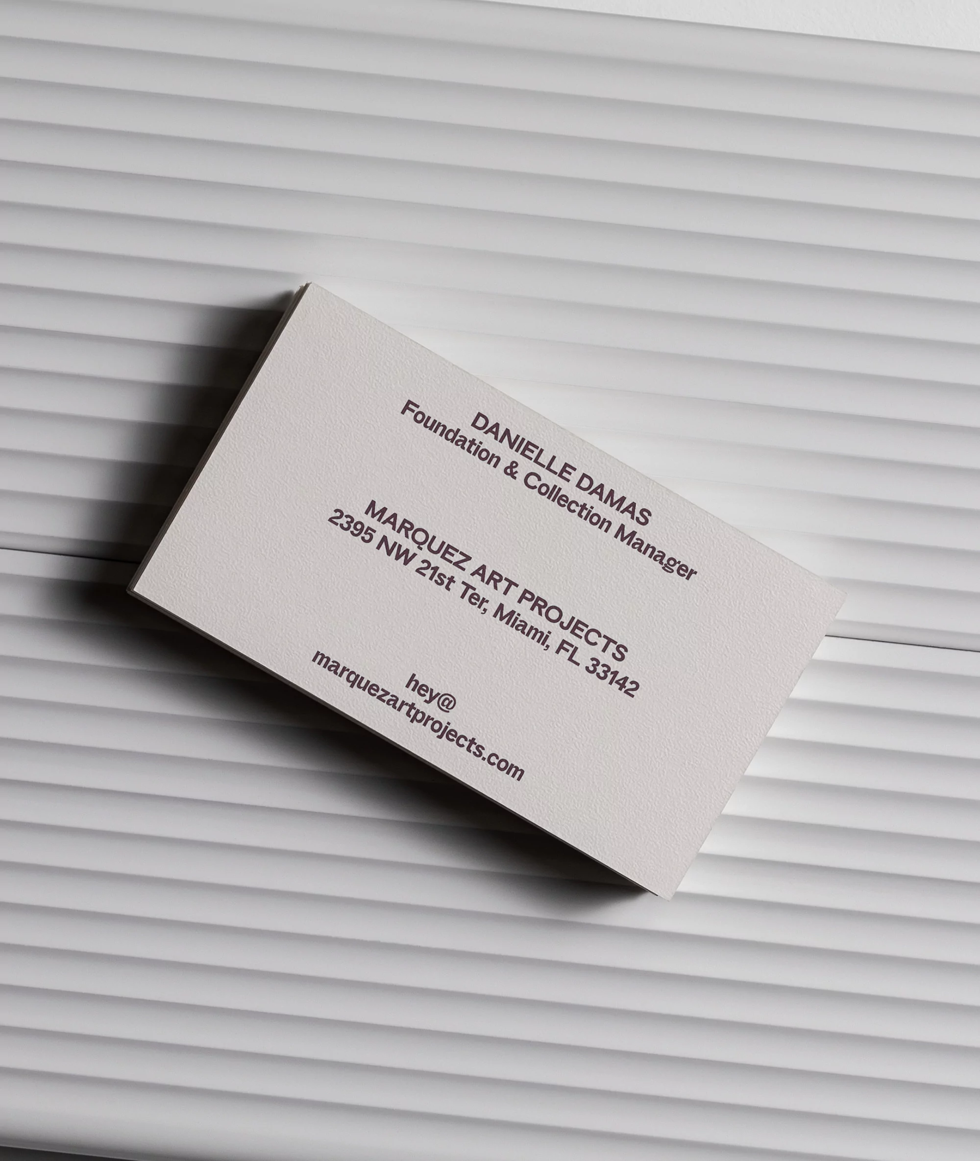 Close-up of a business card on a textured white surface, featuring company and personal contact information in a minimalist style.