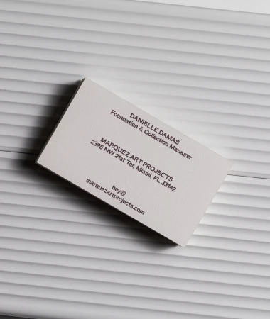 Close-up of a business card on a textured white surface, featuring company and personal contact information in a minimalist style.