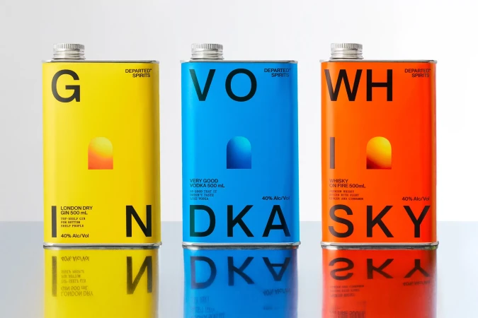 Three colorful gin, vodka, and whisky bottles, distinguished by yellow, blue, and orange labels, neatly arranged on a reflective surface.