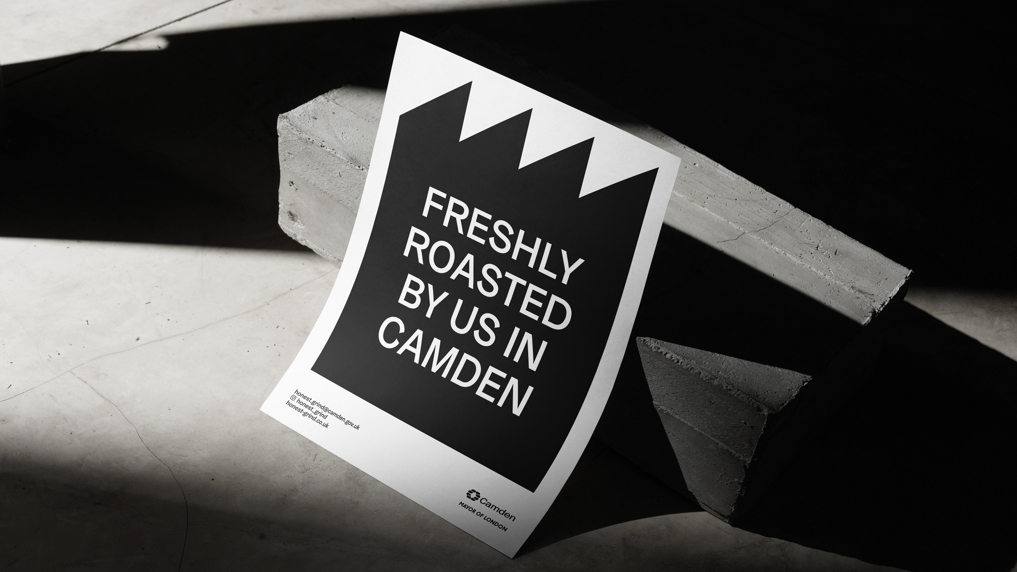 Promotional poster for freshly roasted coffee by Camden, resting against concrete blocks in a studio with bright, graphic lighting.