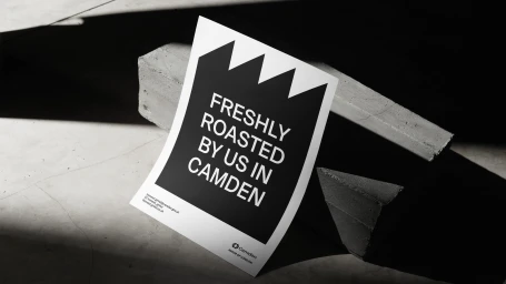Monochrome product poster with bold typography resting on industrial concrete blocks under hard lighting.