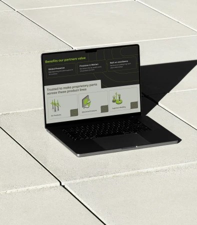 Laptop on concrete surface displays website with graphics and text promoting products and services. Modern design. Focus on business.