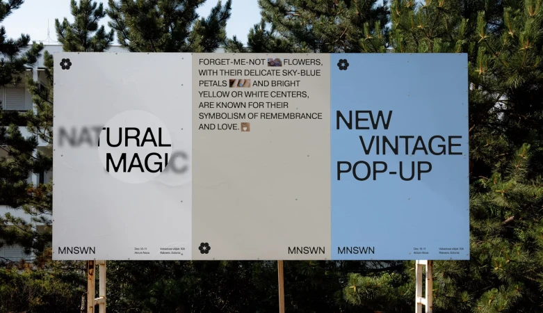 Billboard advertisement featuring 'Natural Magic' and 'New Vintage Pop-Up' texts against a backdrop of trees and building on a sunny day.
