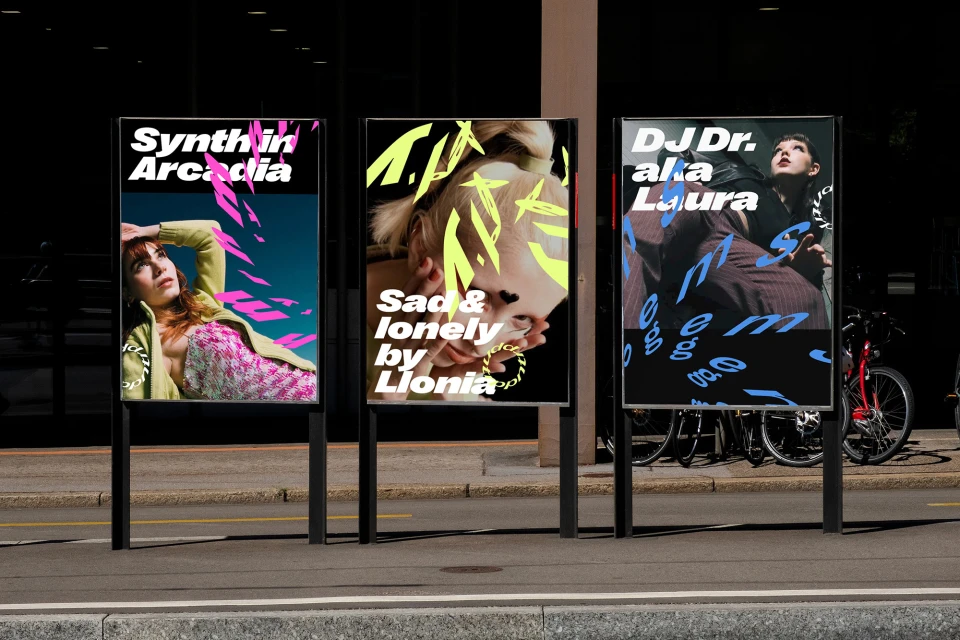 Outdoor shot of three poster stands displaying unique visuals with bold typography, showcasing creative art and music events in urban setting.