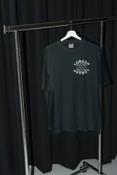 Black t-shirt with white graphic print hanging on white hanger on chrome rack against dark curtains