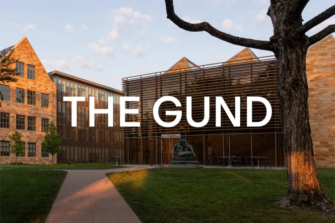 Exterior view of The Gund building featuring modern architecture, stone facade, lawn, pathway, and a sculpture.