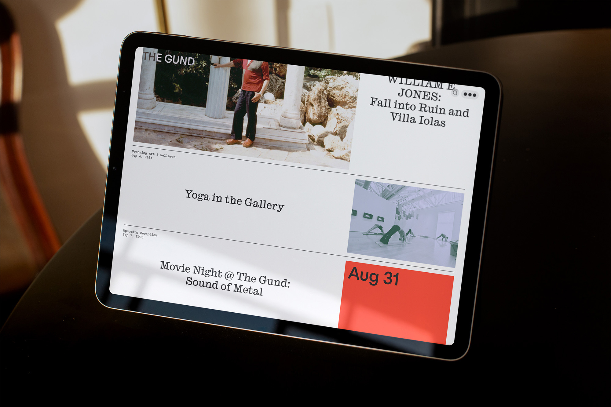 Image of an iPad displaying a webpage featuring events at The Gund, including art exhibitions, yoga, and movie nights, laid on a dark surface.