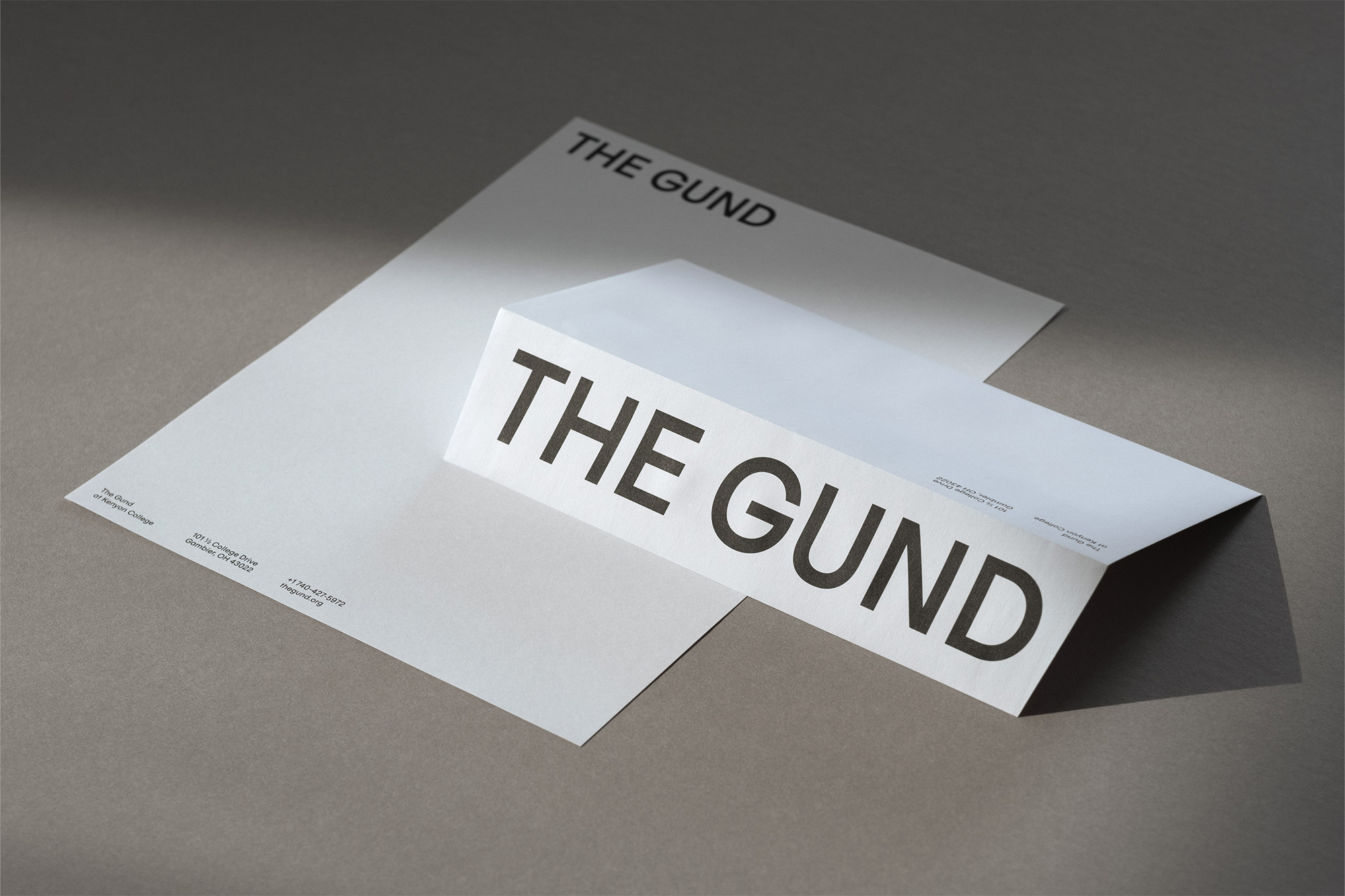 Minimalist stationery featuring 'THE GUND' typography with a clean, folded design and a light grey background, creating a modern, professional aesthetic.