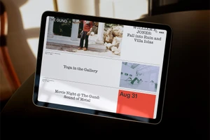 Tablet displaying a modern web page design for The Gund with event listings against a dark wooden surface.