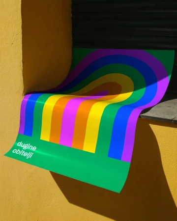 Colorful striped poster is affixed to a yellow wall, featuring rainbow arches and the text 'dugine obitelji' at the lower left.