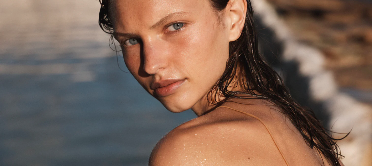 Close-up portrait of a fair-skinned woman with wet, dark hair, featuring a shallow depth of field and natural lighting.