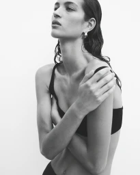 Monochrome portrait of a woman with wet hair wearing a black top against a plain light background by Tim Ashton.