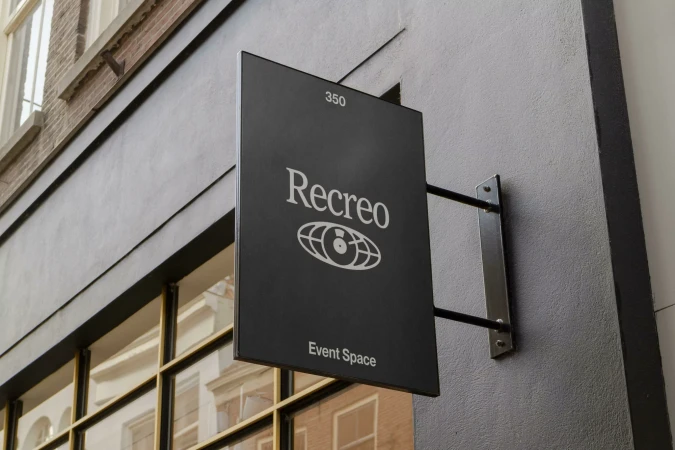 Black rectangular storefront sign mounted on a grey building exterior with white typography reading Recreo and Event Space.