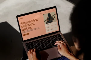 Close-up of a laptop displaying the Sunday Wellness website while a person types on the keyboard.