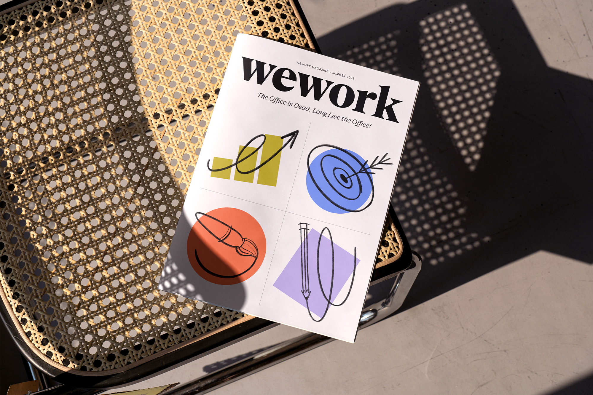 Wework magazine laying on a wicker chair. The cover features colorful line art illustrations on a white background. 