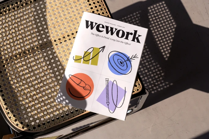 Wework magazine laying on a wicker chair. The cover features colorful line art illustrations on a white background. 
