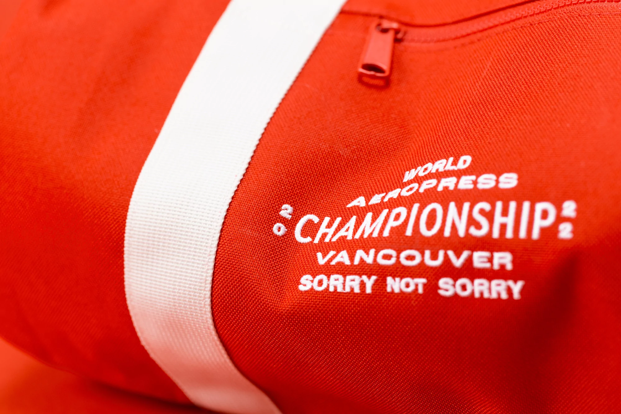 Close-up of a bright red duffel bag with white stripes and white lettering that says 'World Aeropress Championship Vancouver'.