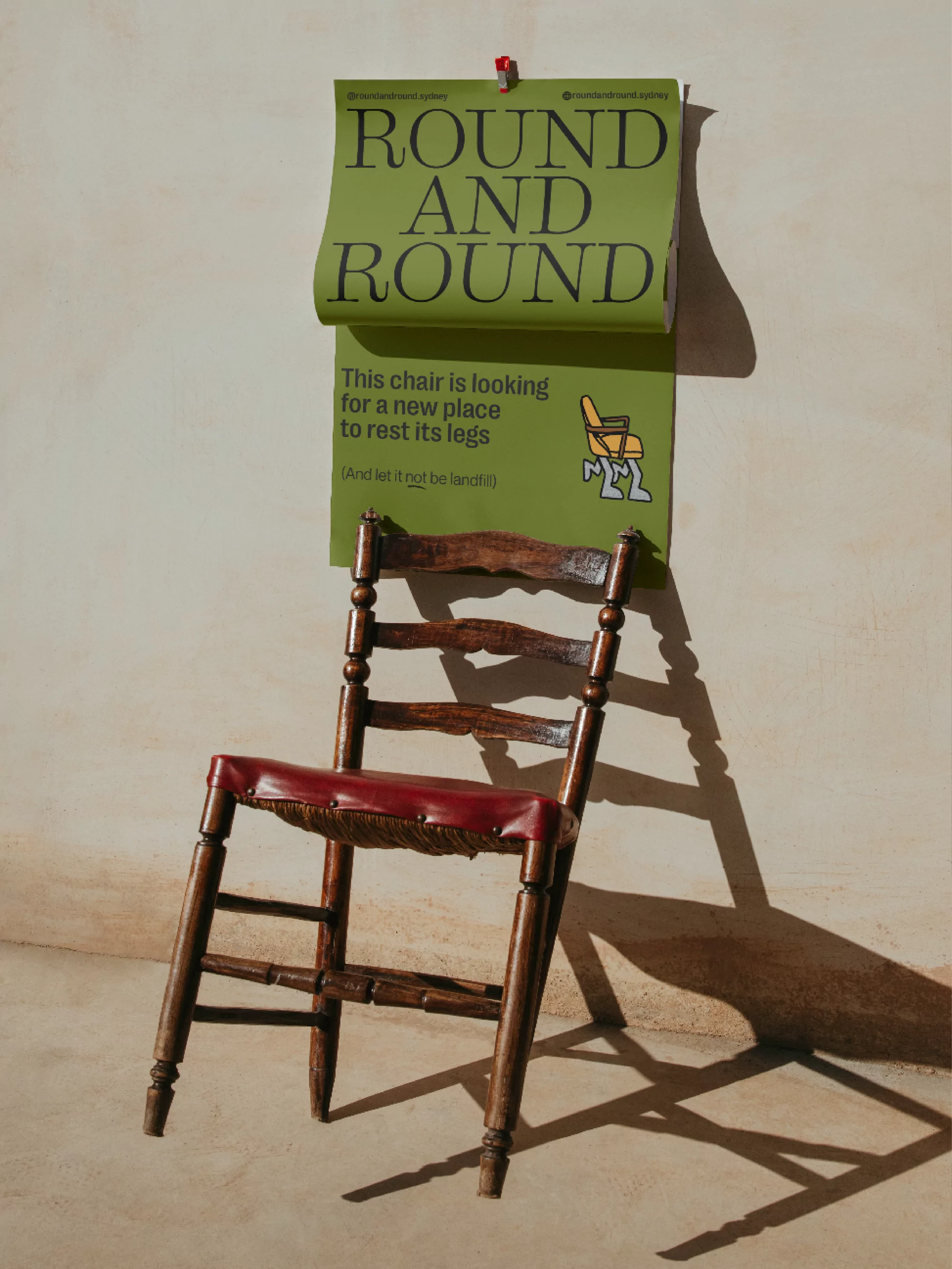 Wooden chair displayed next to a green poster with black text; the poster reads 'Round and Round' and a description for the chair.