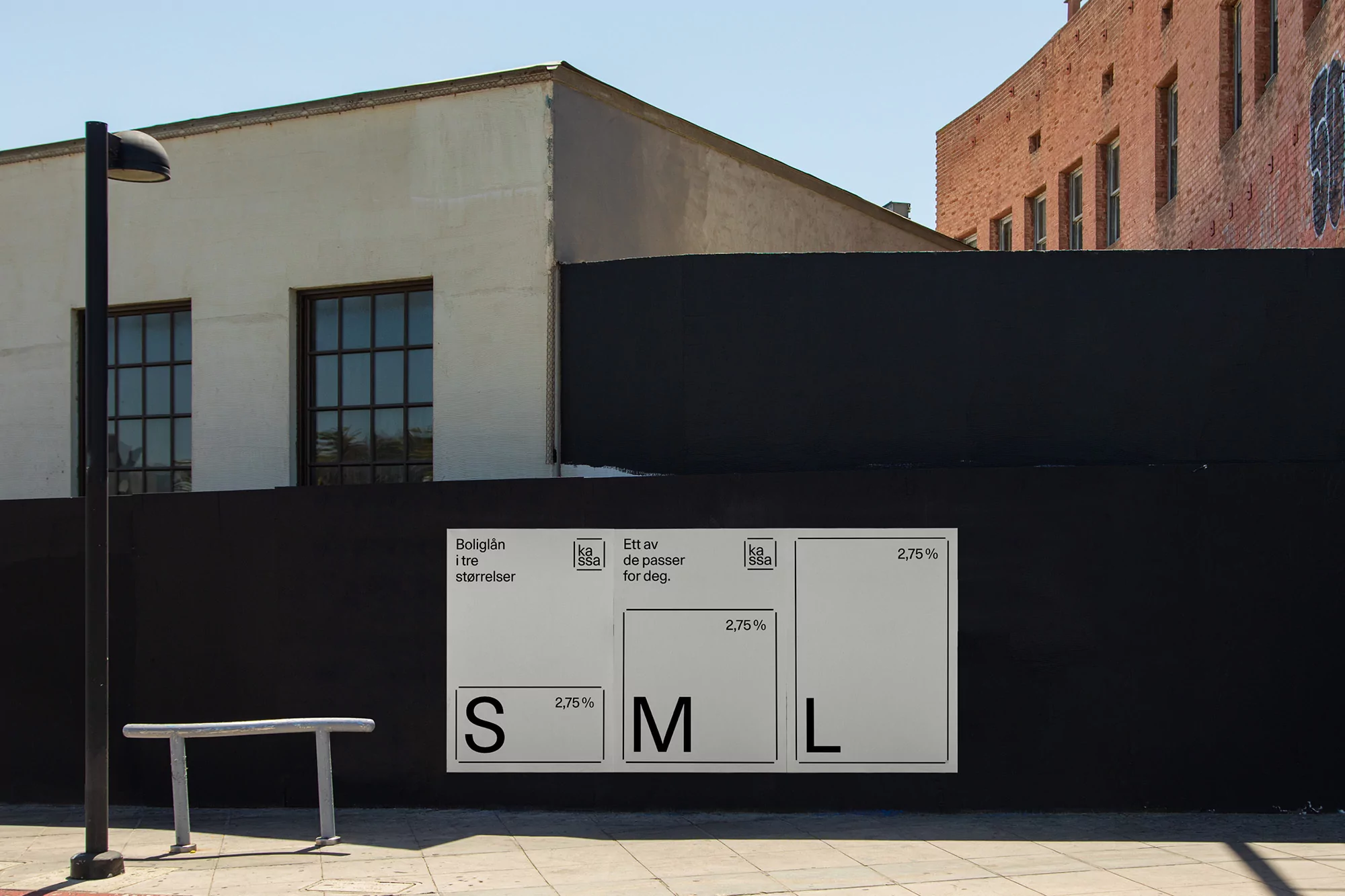 Outdoor advertising featuring block letter art on a dark wall with the letters S, M, and L in boxes on an urban street.