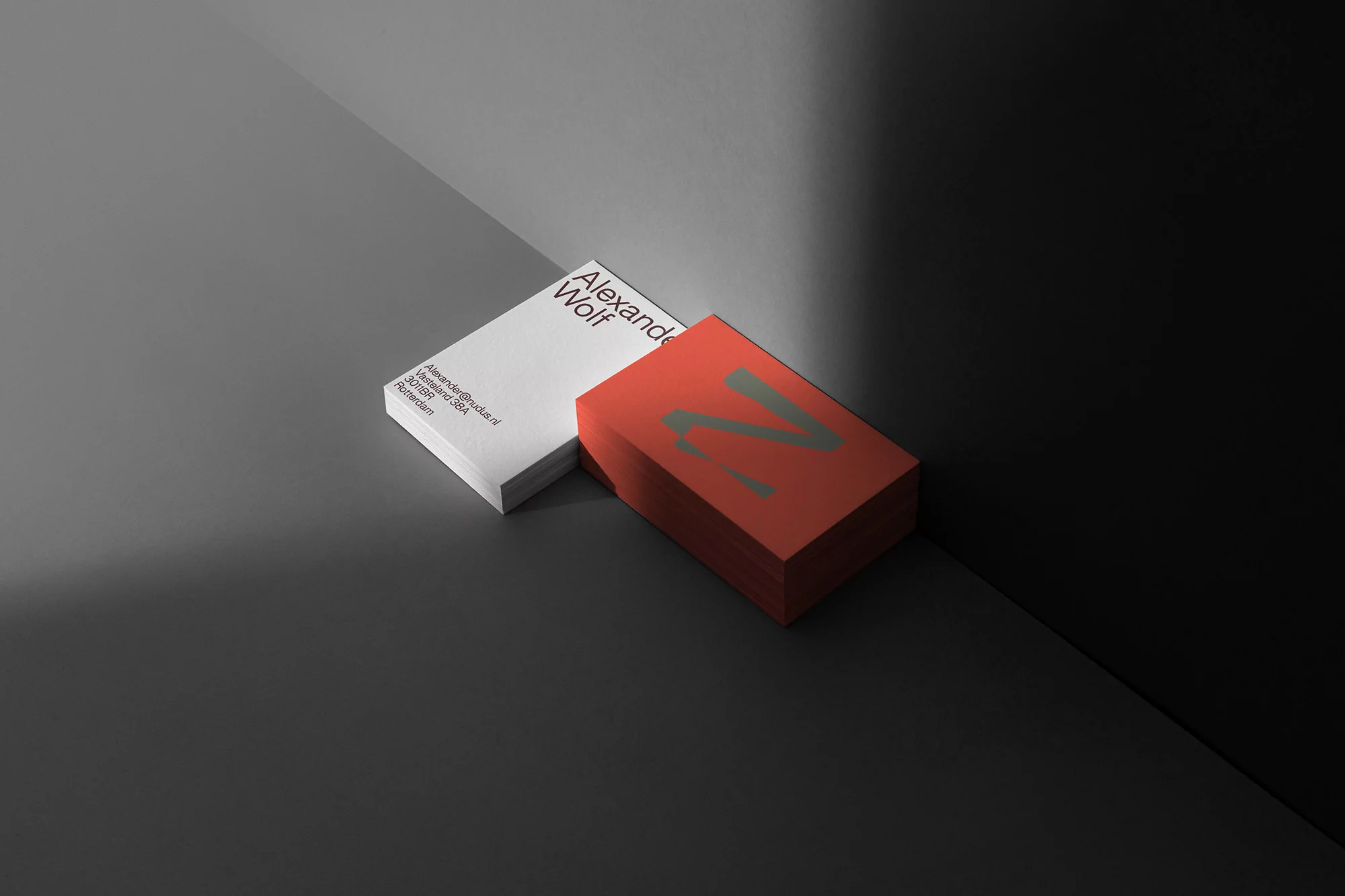 Two stacks of business cards, one white with text and one red with logo, rest on a grey surface, showcasing minimalist design.